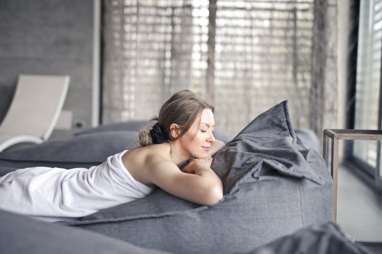 A serene moment indoors as a woman relaxes on a couch, enjoying a peaceful spa day.